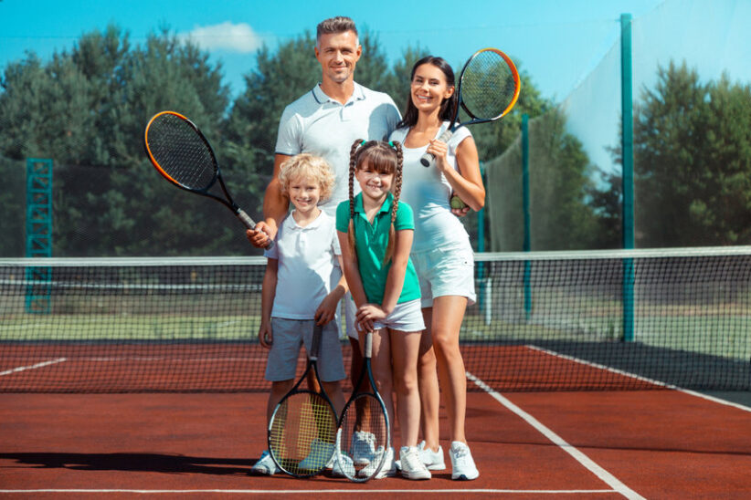 Happy and cheerful. Fit and active parents and children feeling happy and cheerful after playing tennis
