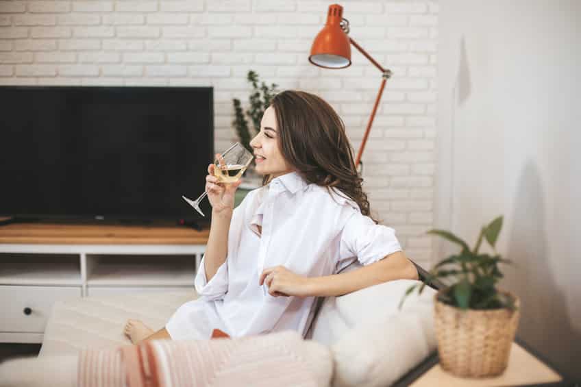 Young woman with glass of wine at home.