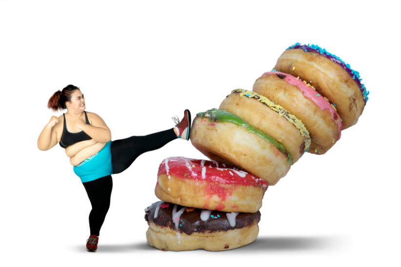 Obese woman kicking stack of donuts