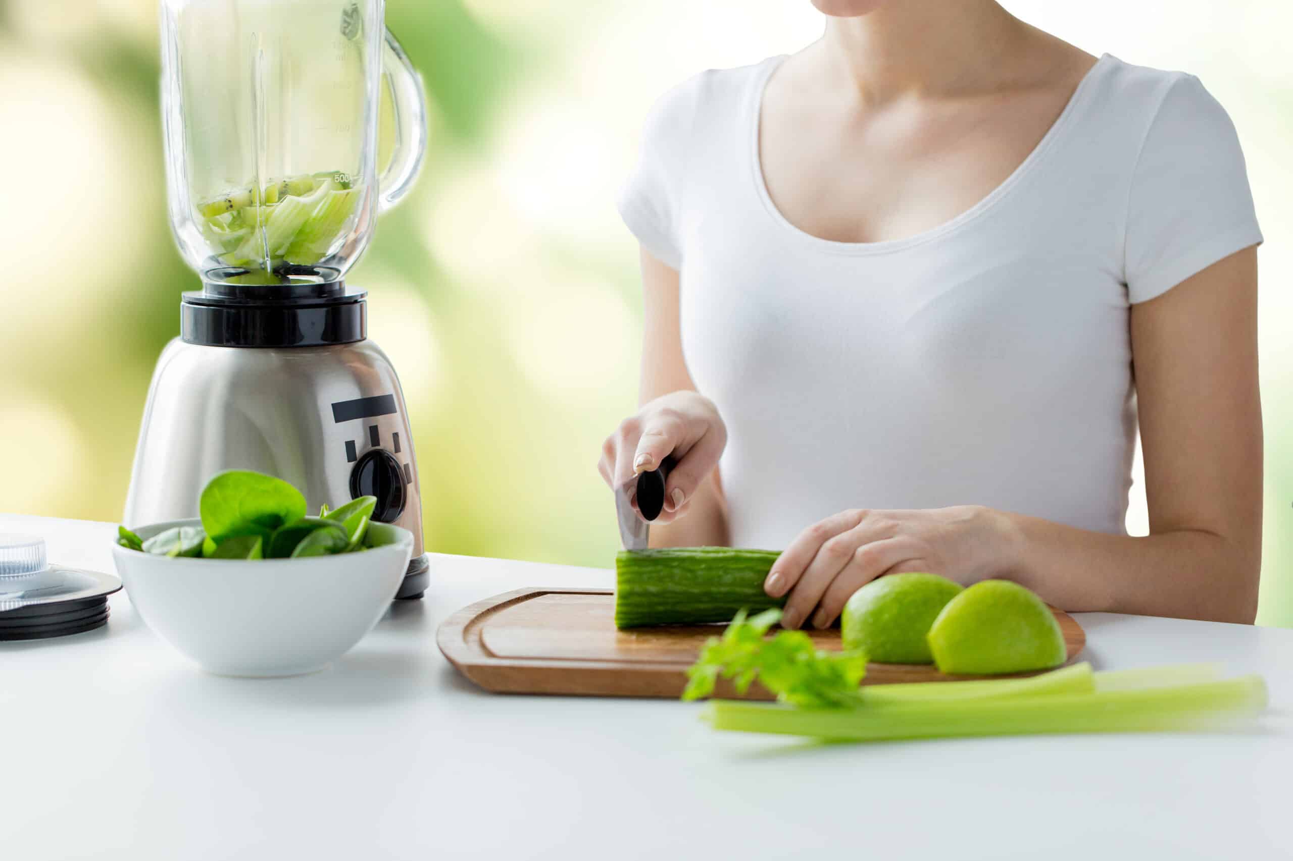 close up of woman with blender chopping vegetables