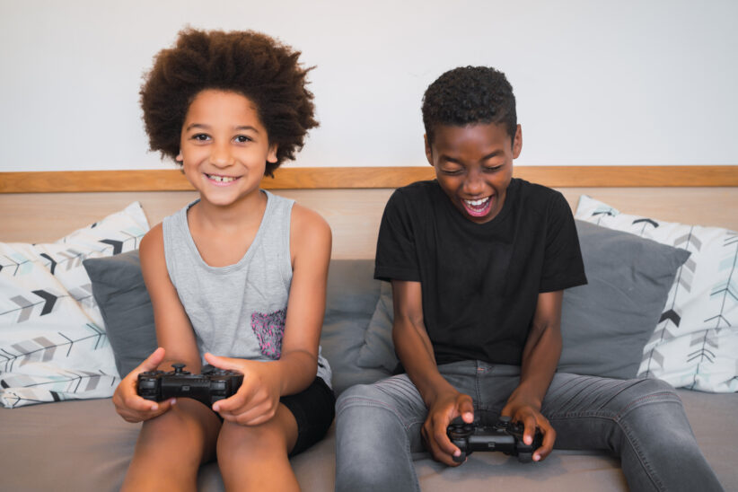 two Afro American brothers playing video games at home.