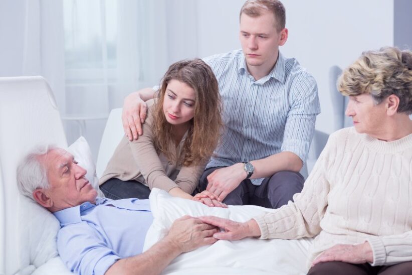 Man in hospital bed surrounded by family